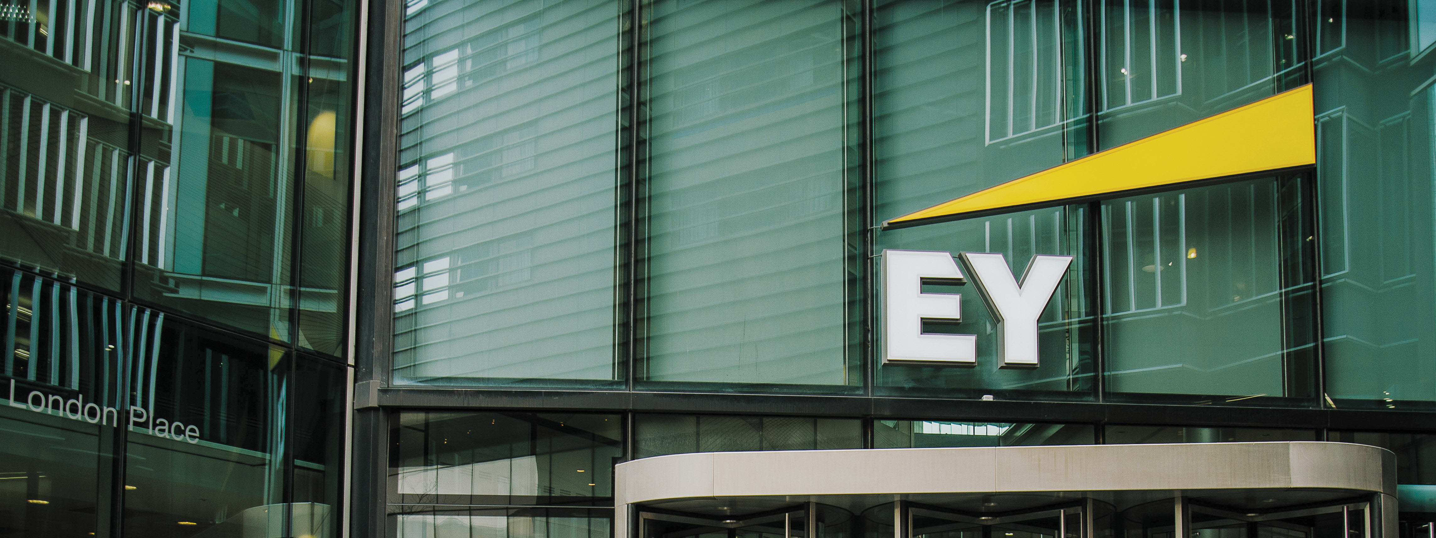 A photo of the EY logo on the facade of the EY headquarters building in London.