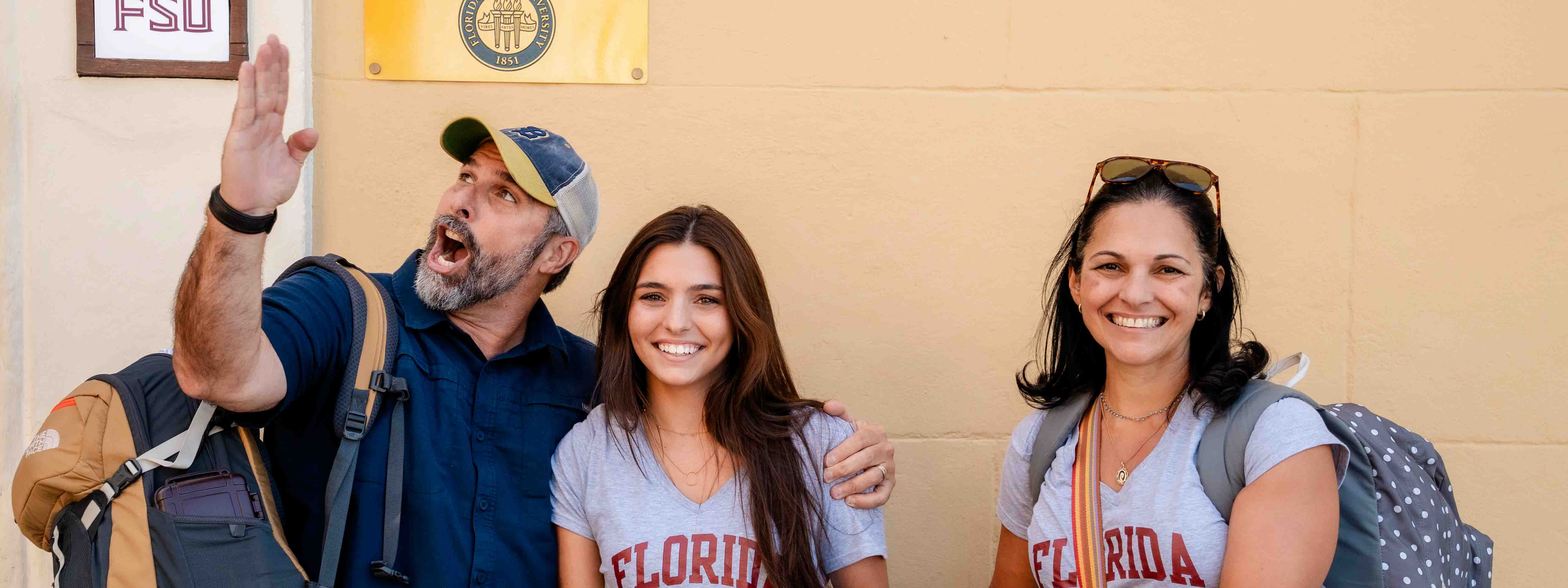 A student with her parents in Valencia. The dad is doing an FSU chop and the mom and daughter are smiling.