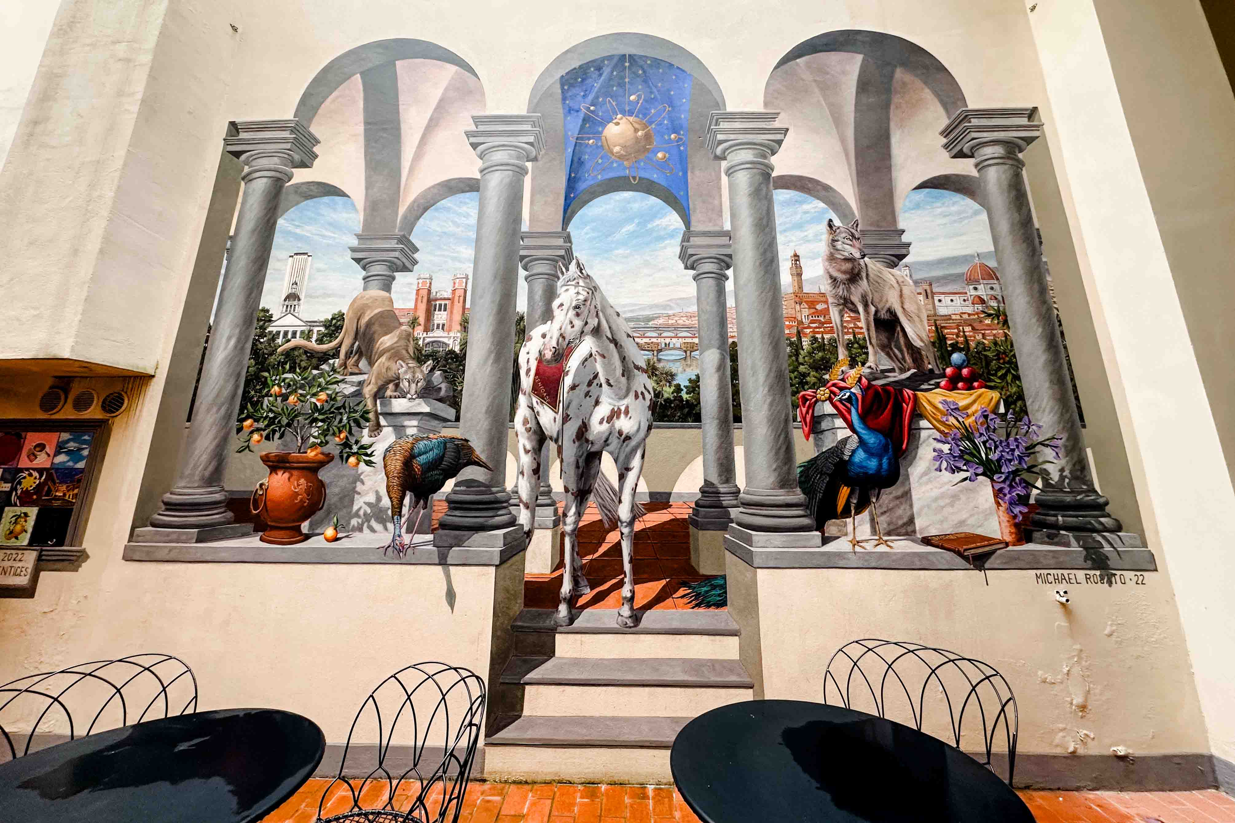 FSU Florence's outdoor mural with patio tables and chairs in the foreground.