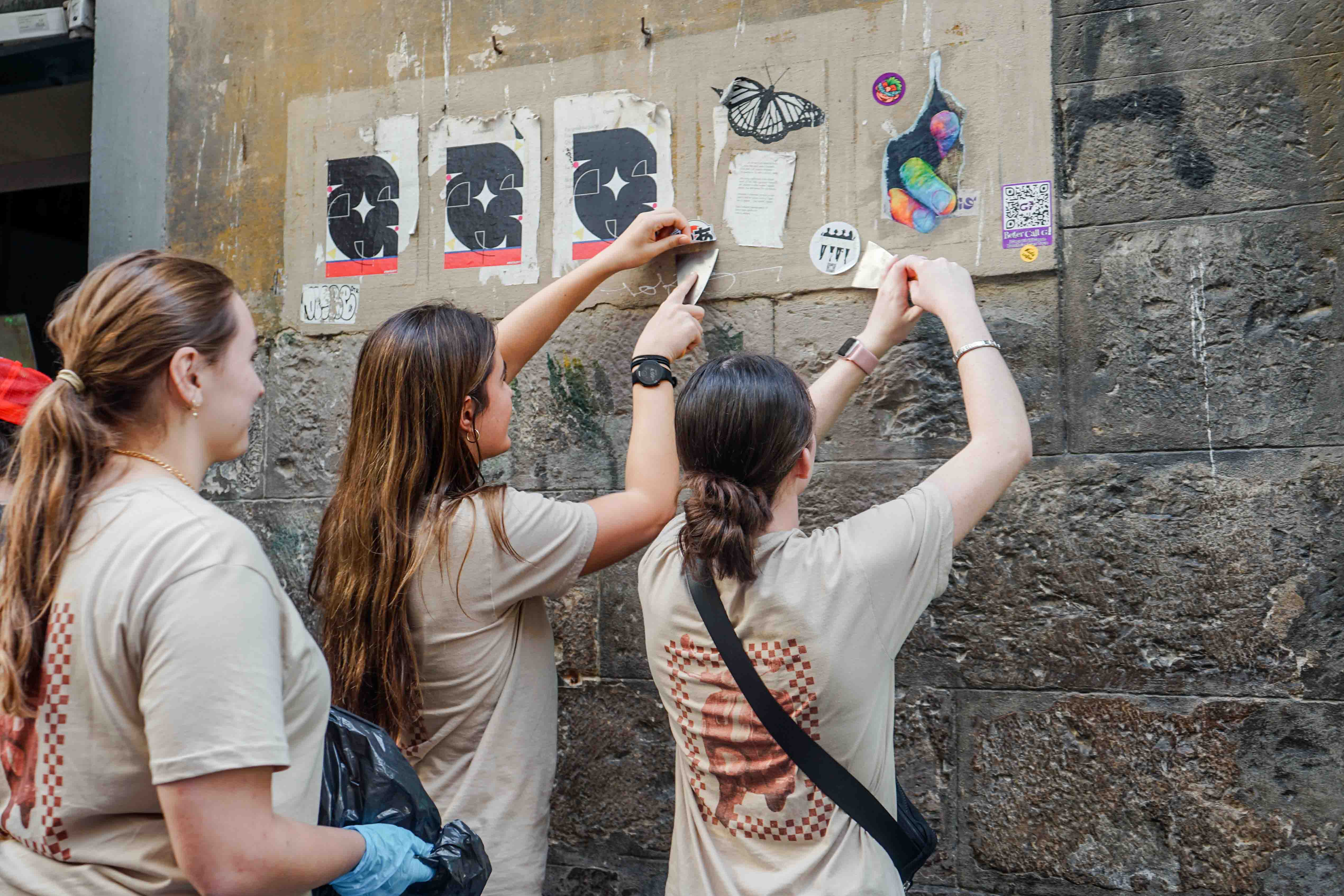Students volunteering by cleaning up old posters on the streets of Florence.