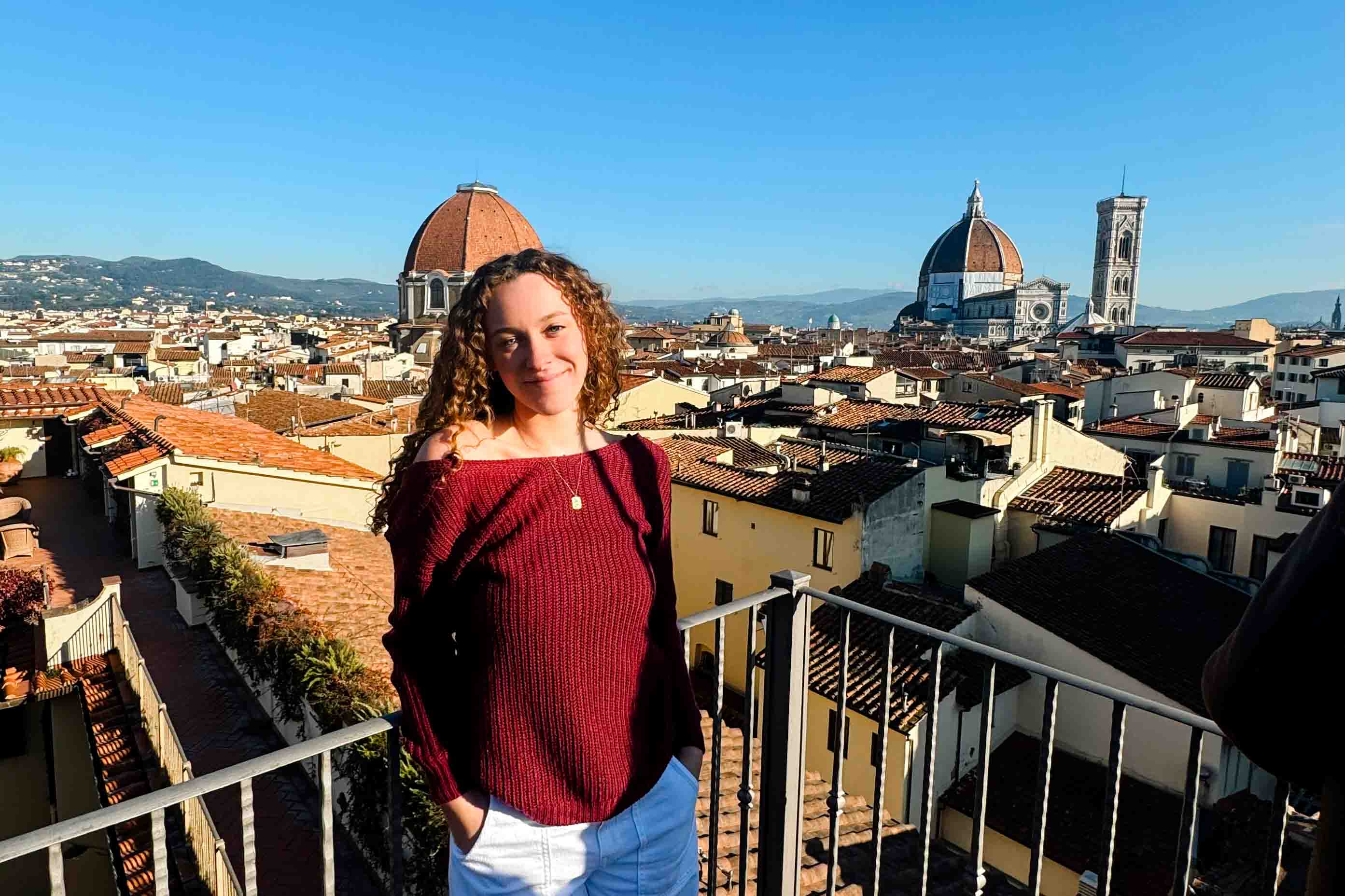 A student on a rooftop in Florence with the Duomo in the background.