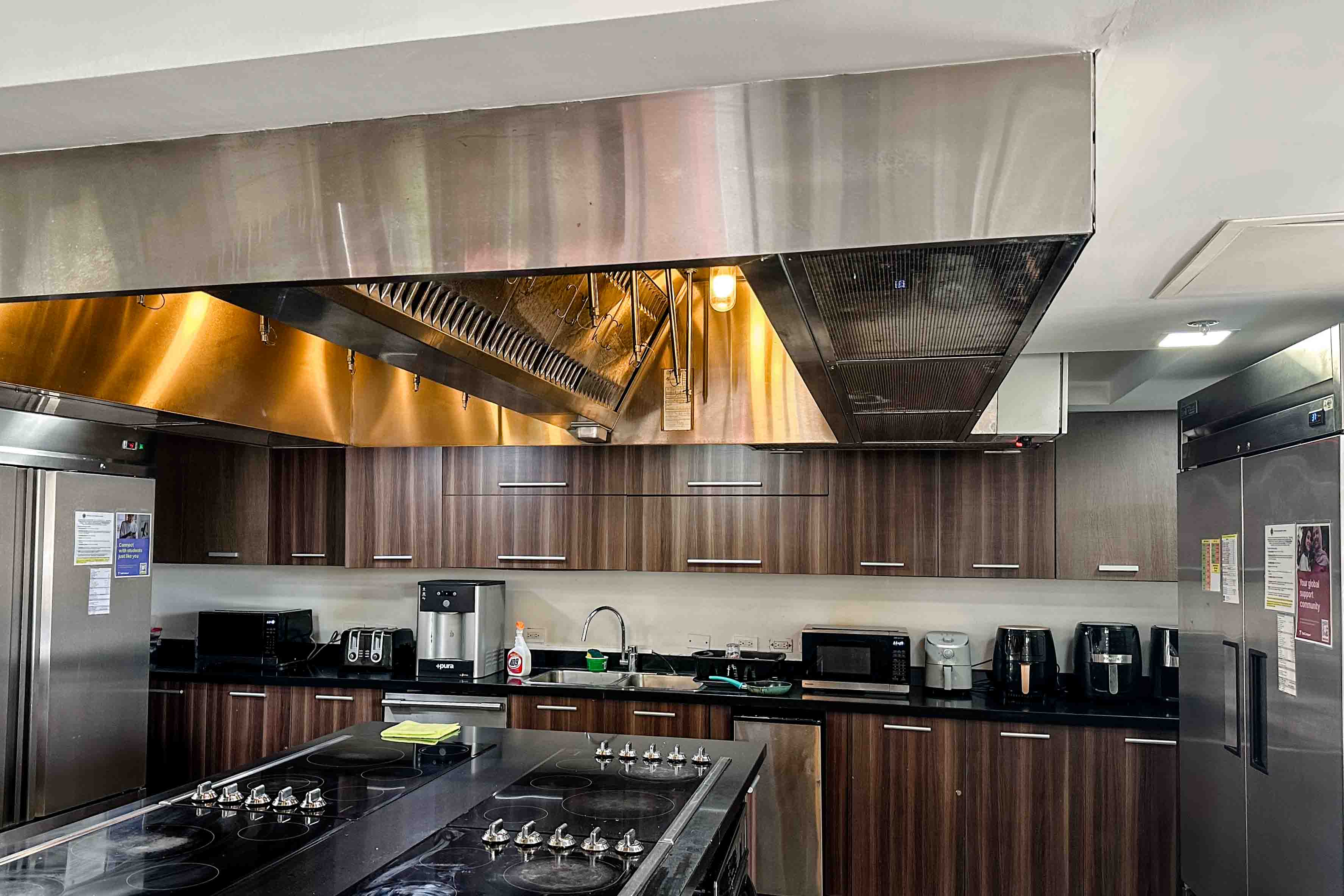 A view of shared kitchen with ranges and refridgerators.