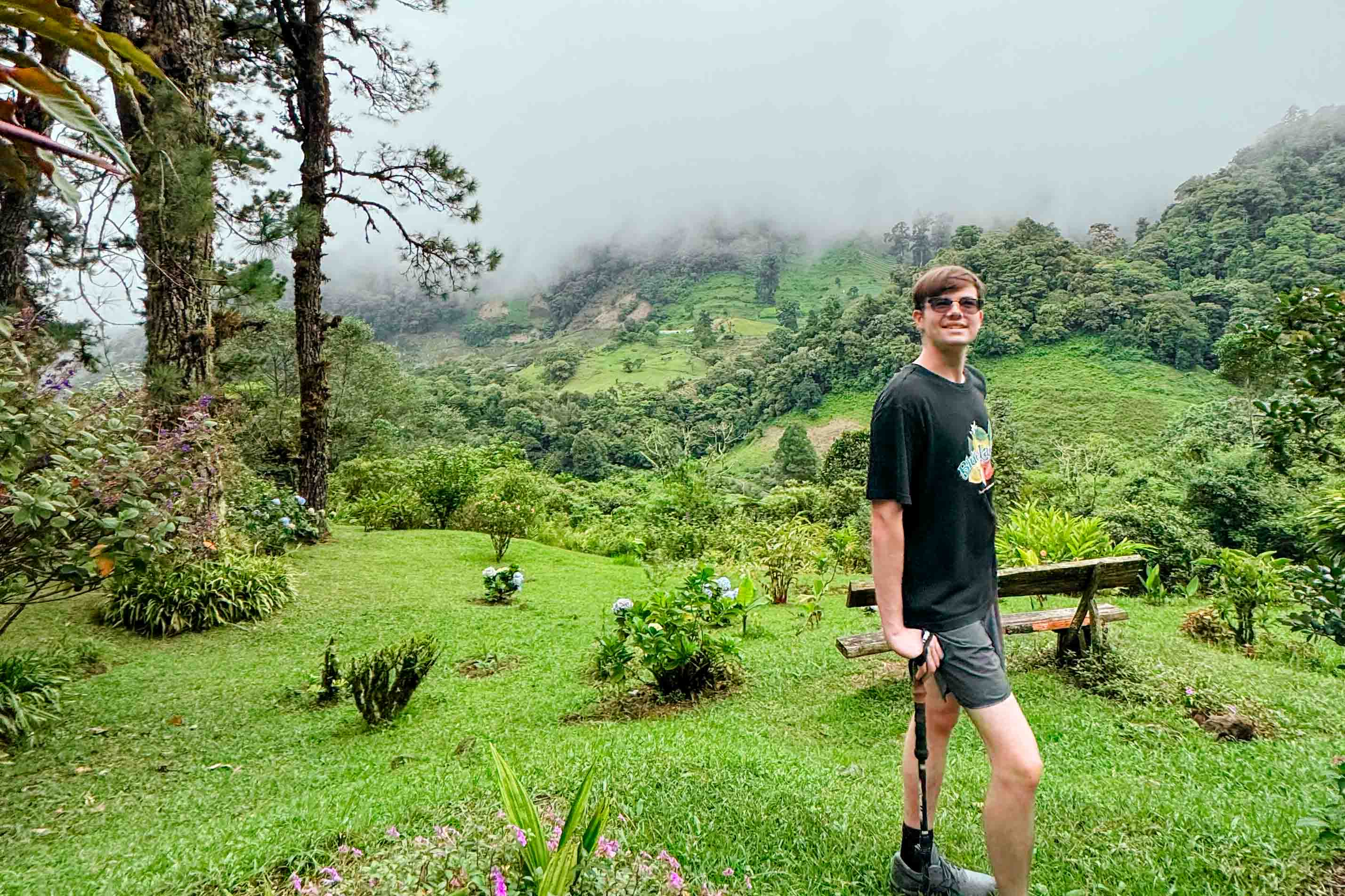 A student posing amongst greenery in the rainforest with cloudy mist around.