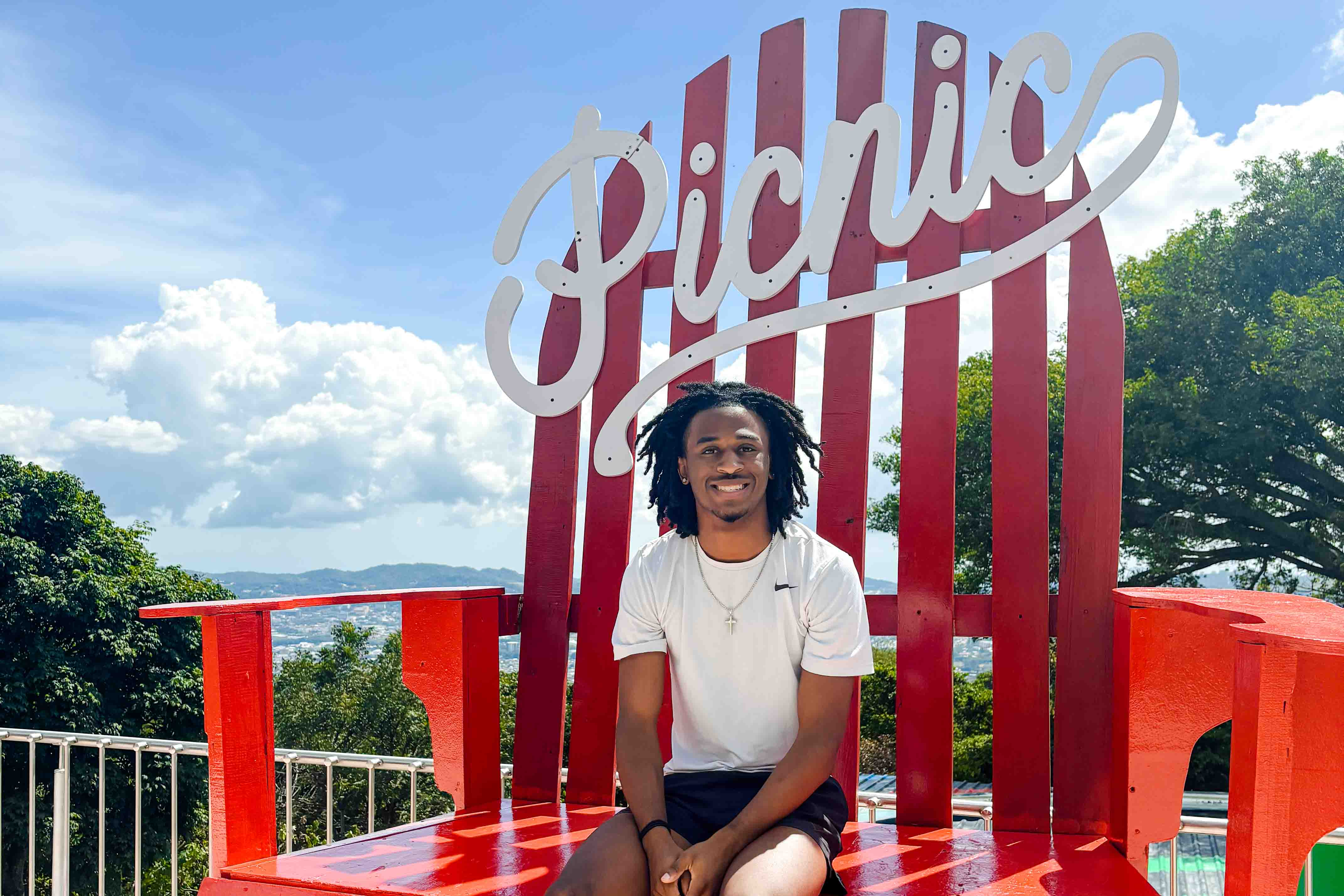 A student sits on an oversized lawn chair outside.