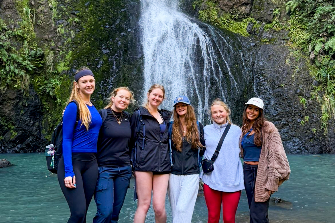 Students posing in front of a waterfall in New Zealand.
