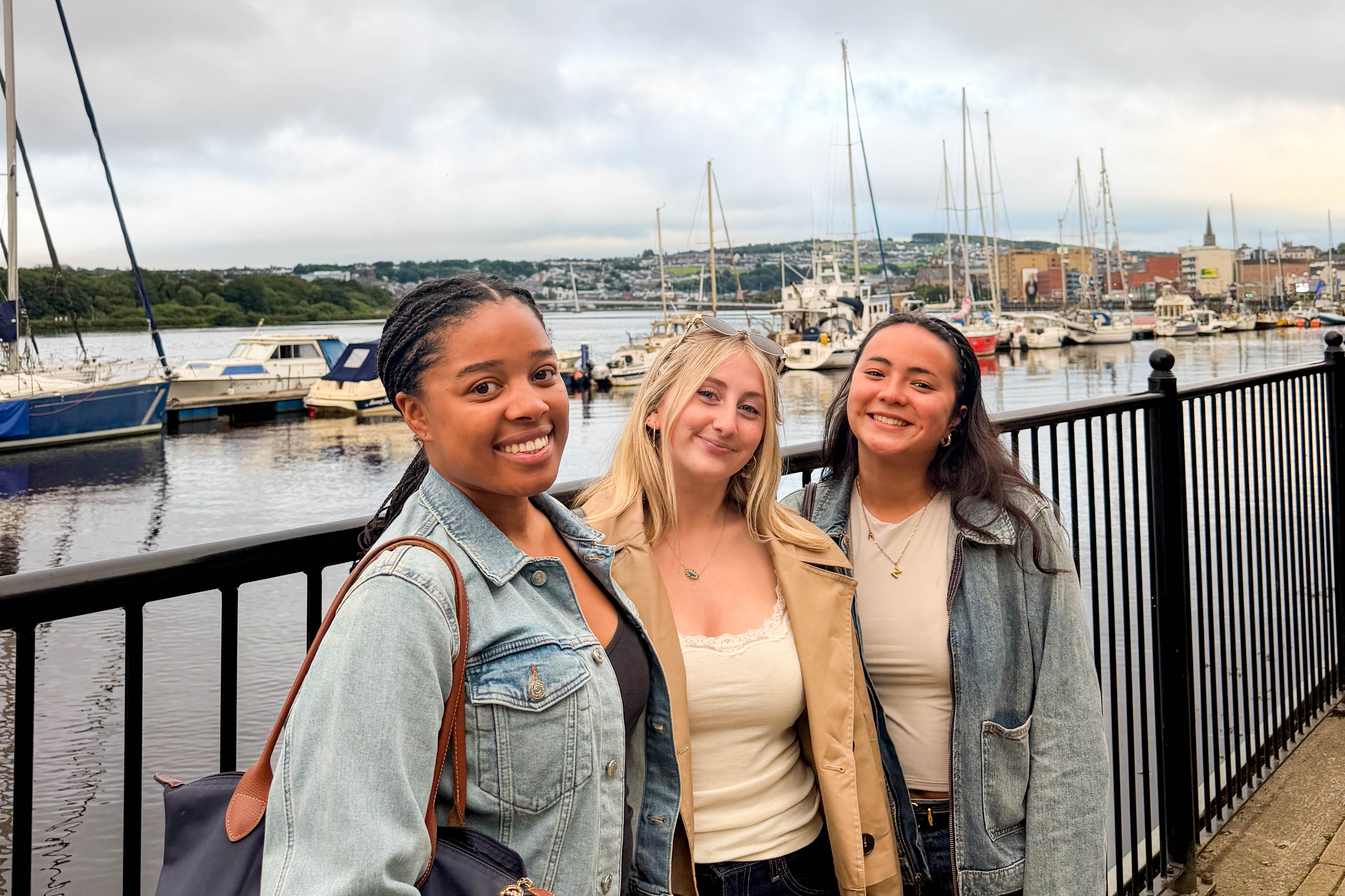 Students posing in front of boats in a harbor.