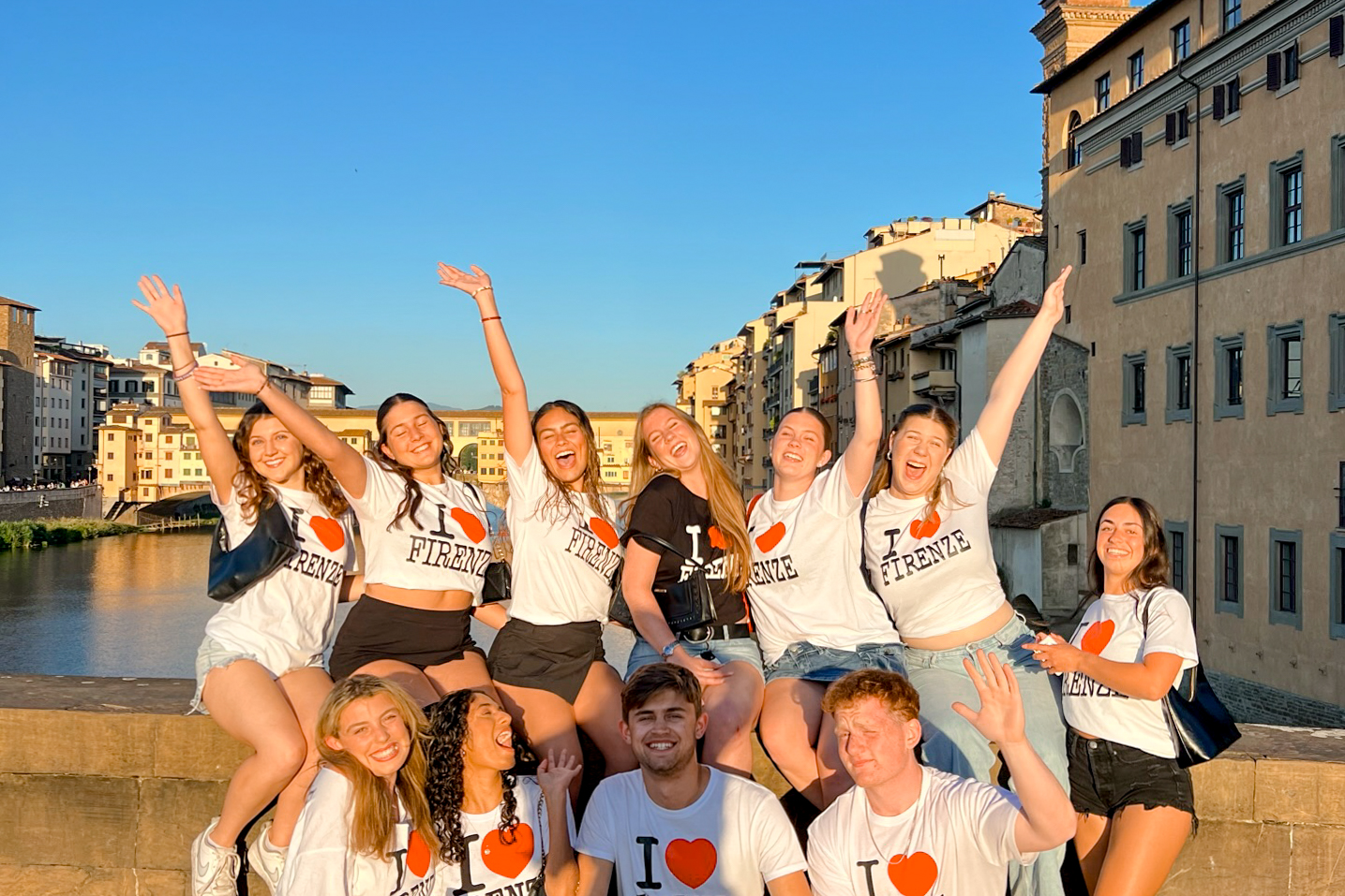 Students excitedly posing in I heart Florence shirts in Florence in front of the Arno river