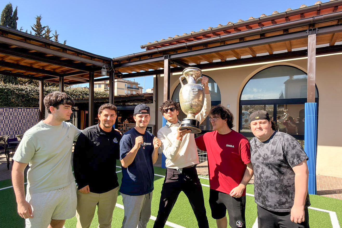 Students posing with sports trophy during class visit.