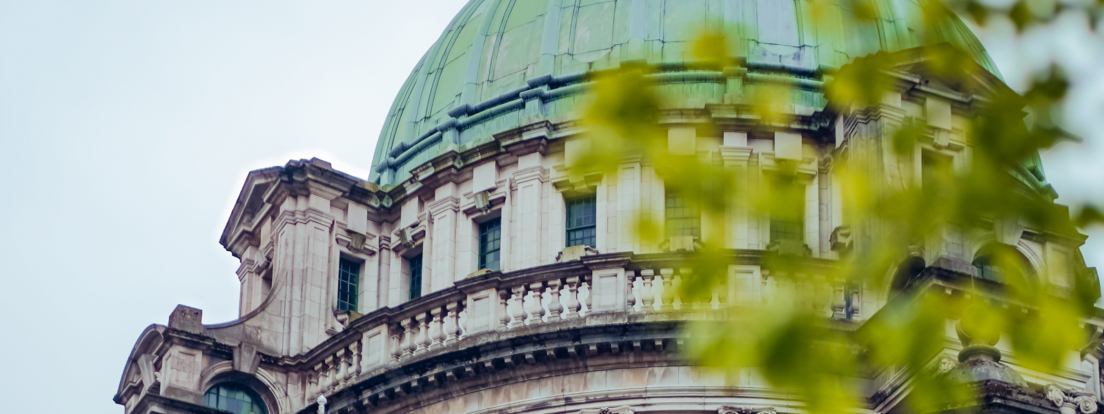 A view of a building dome with foliage in the foreground in Belfast.