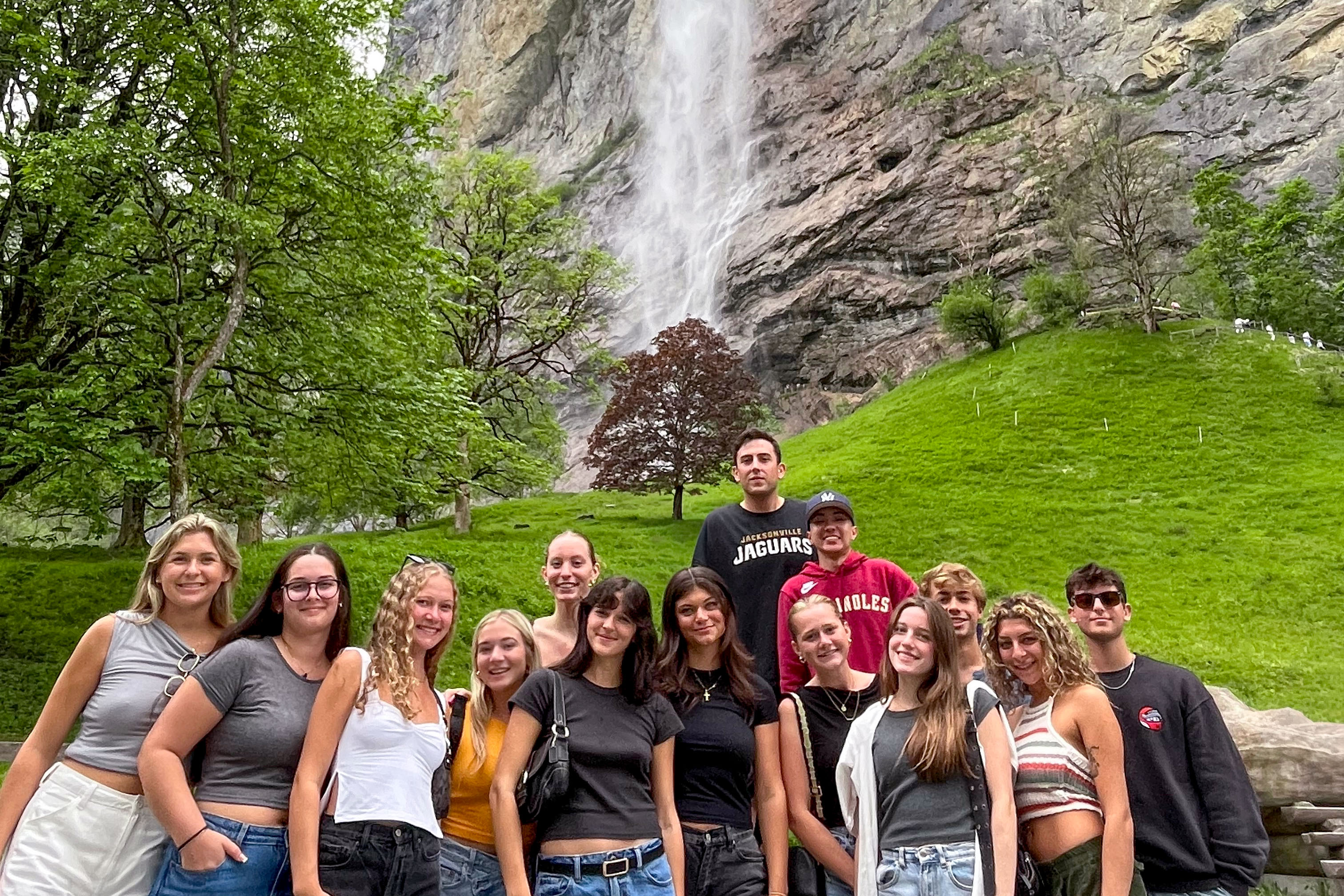 Students posing in front of a waterfall in Switzerland.