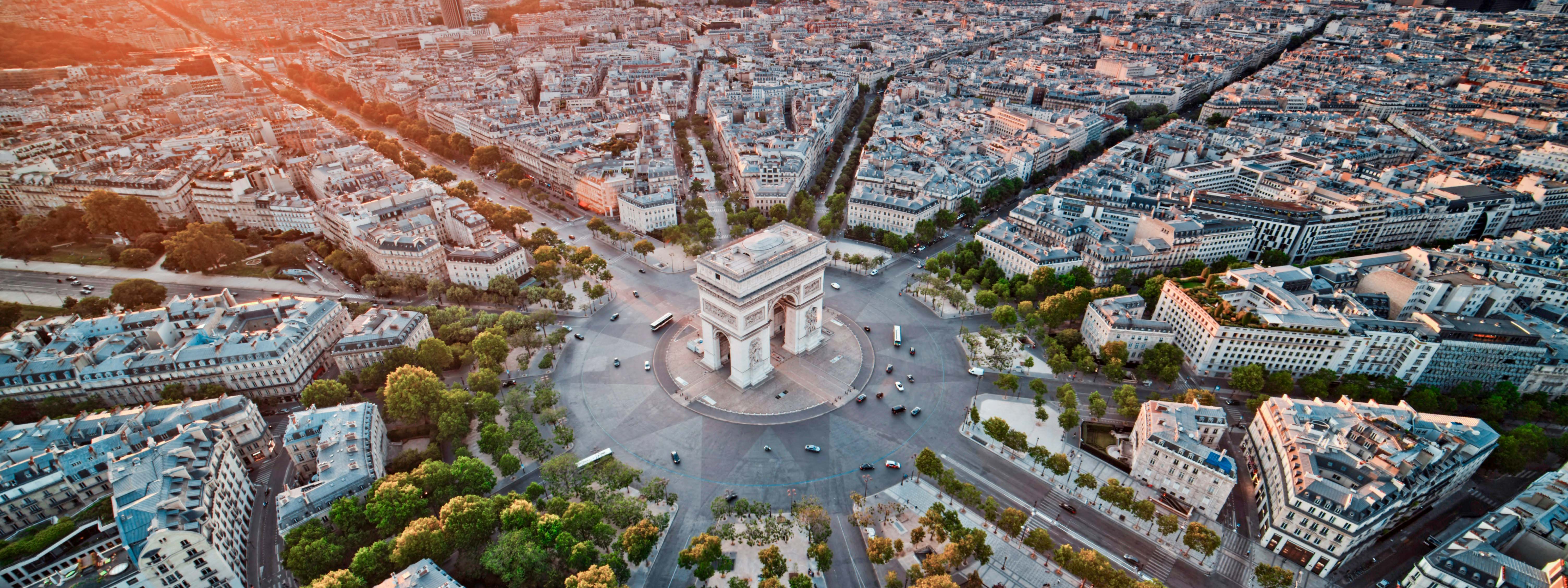 An aerial view of the Arc de Triomphe and surrounding streets in Paris. 
