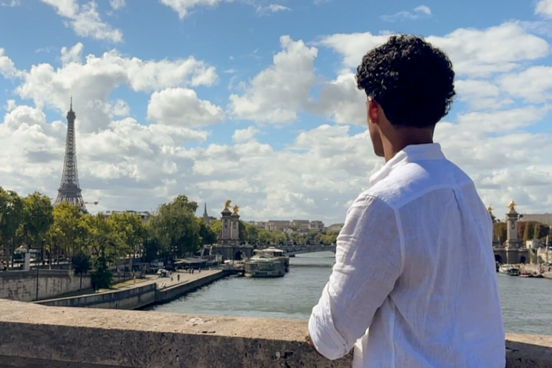 A student looking over the River Seine at the Eiffel Tower in the distance.