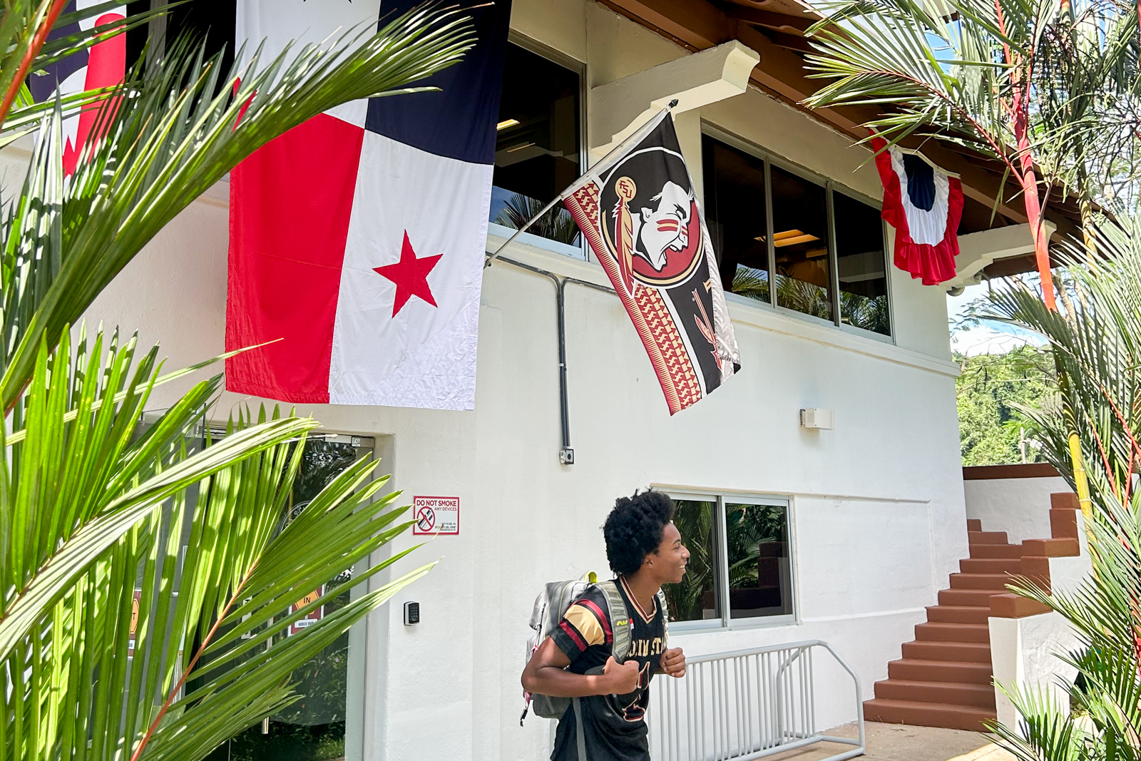 A student walking at the FSU Panama building with a backpack.