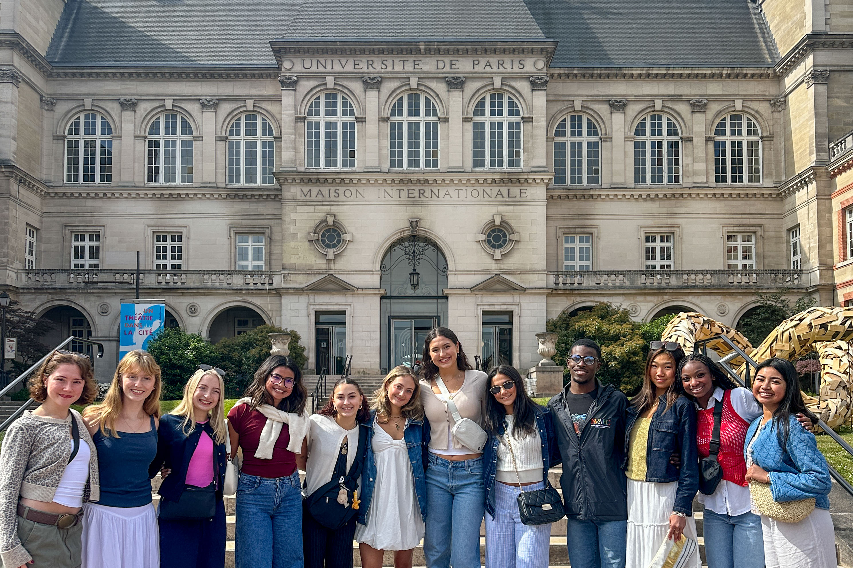 Students posing together in front of the Cite Universitaire where they are housed.