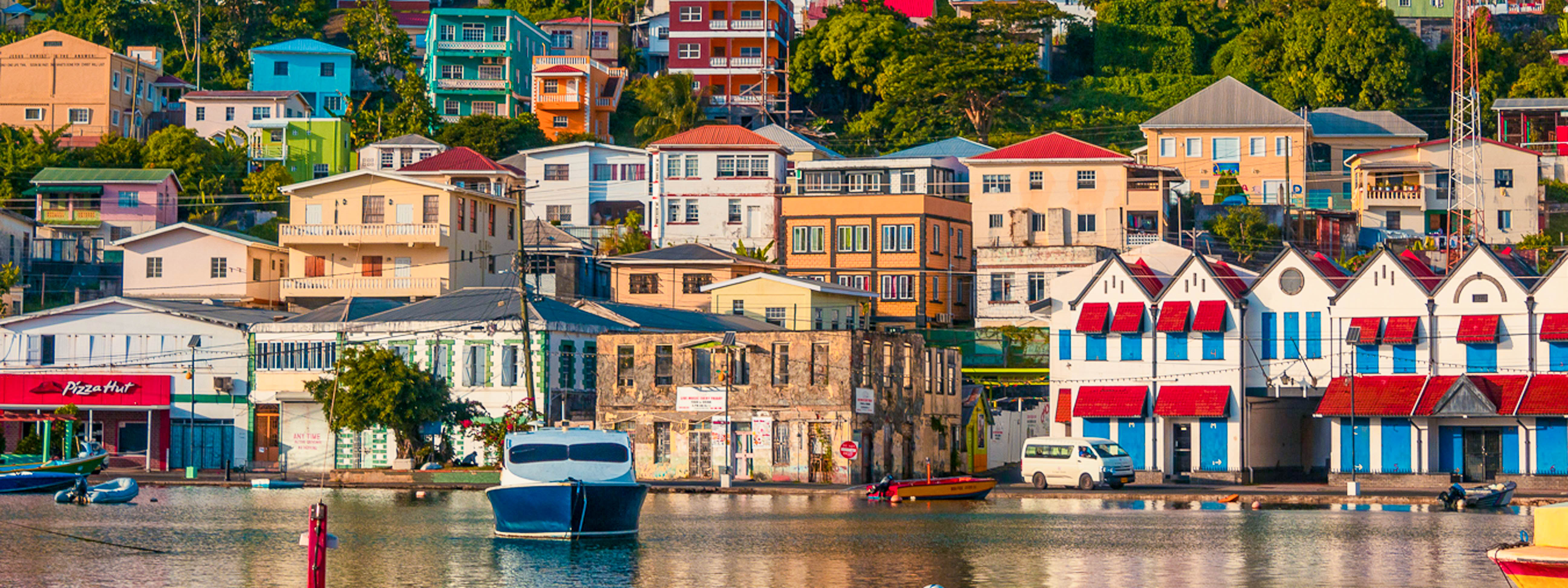 A view of the harbor in Grenada with colorful boats and buildings.