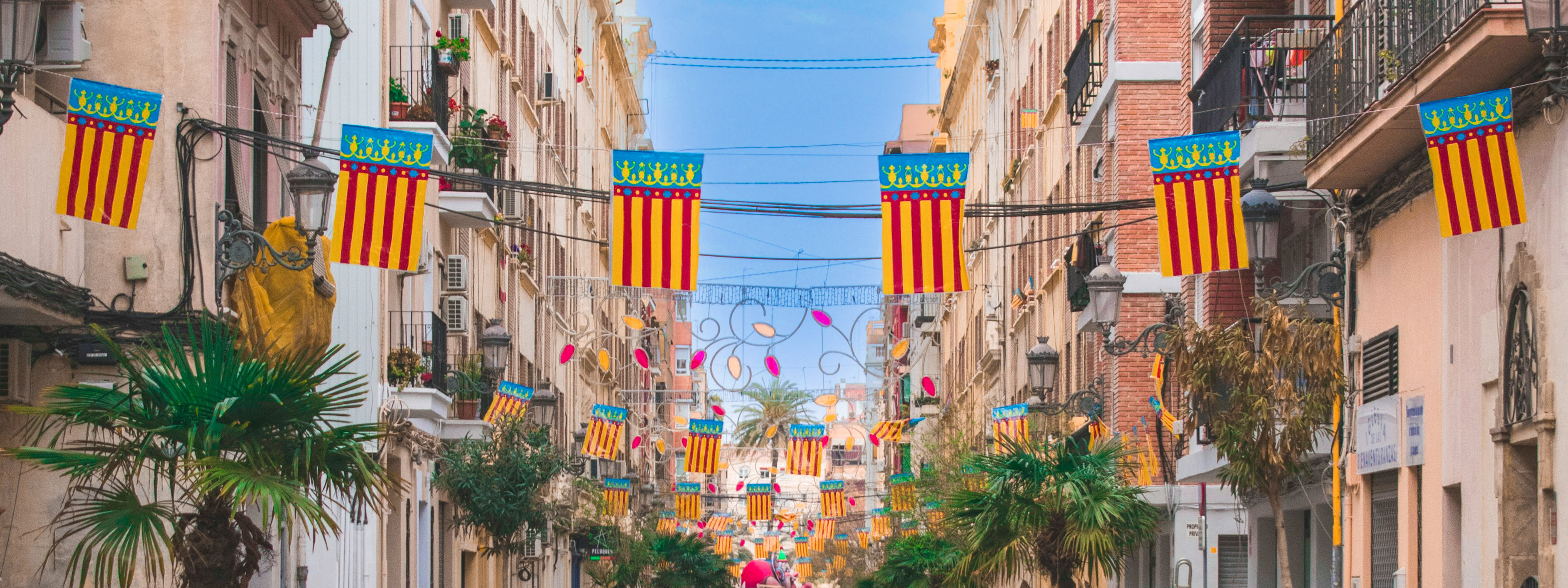 A view of a Valencian street with flags hanging during the spring Fallas festival.