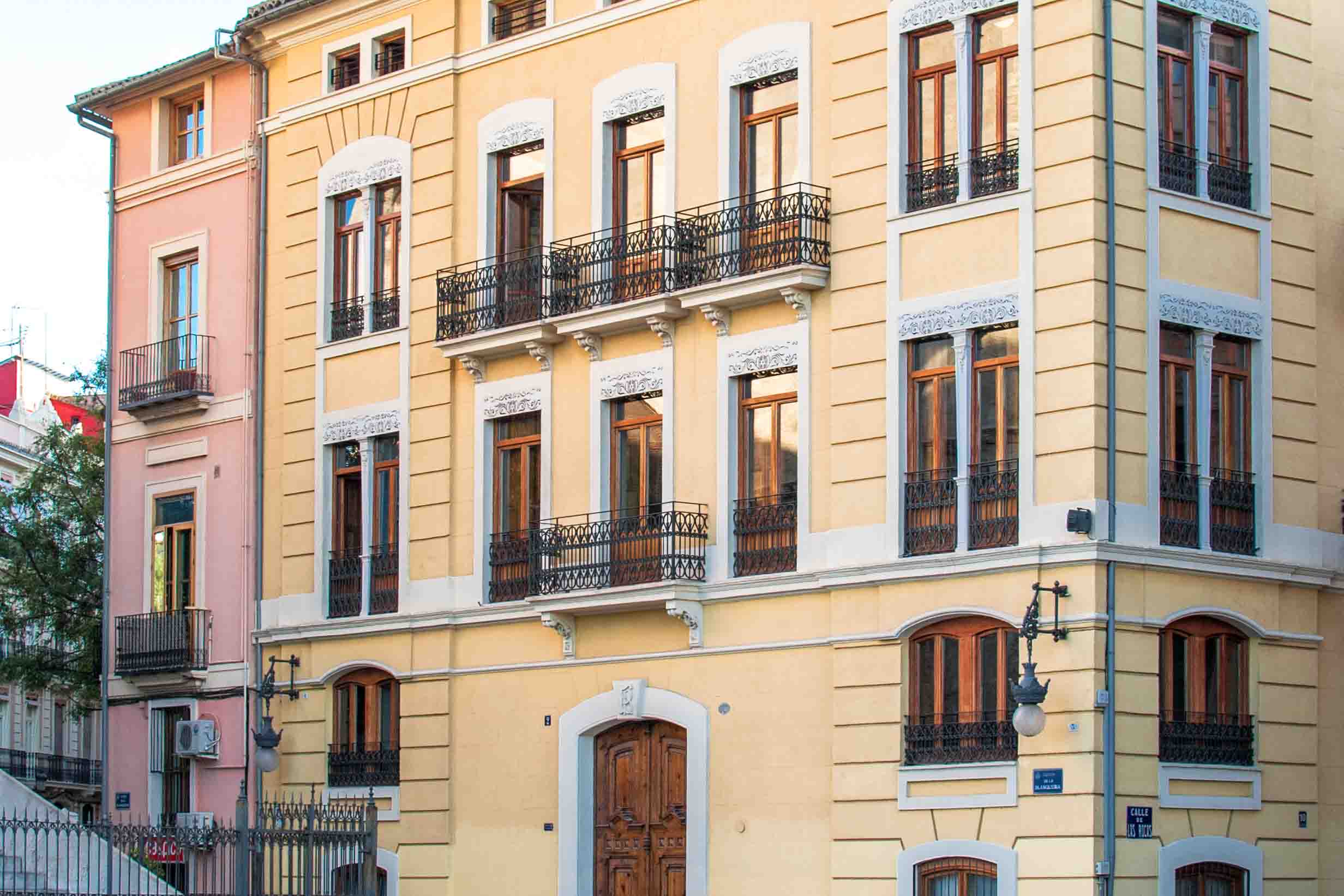 A closer view of the yellowy-gold study center building with a large door and windows and balconies.