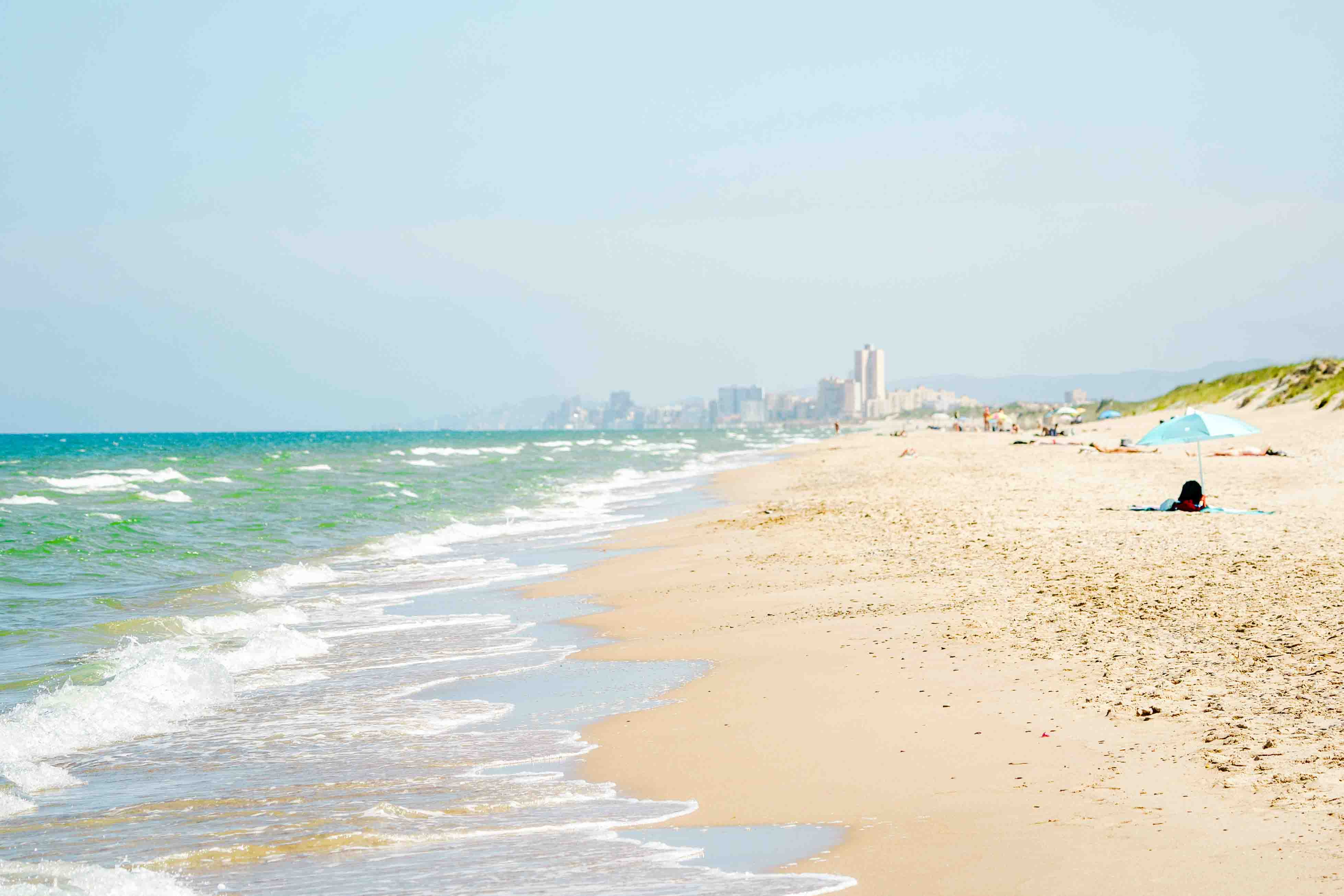 The nearby beach in Valencia with white sand and turquoise Mediterranean water.
