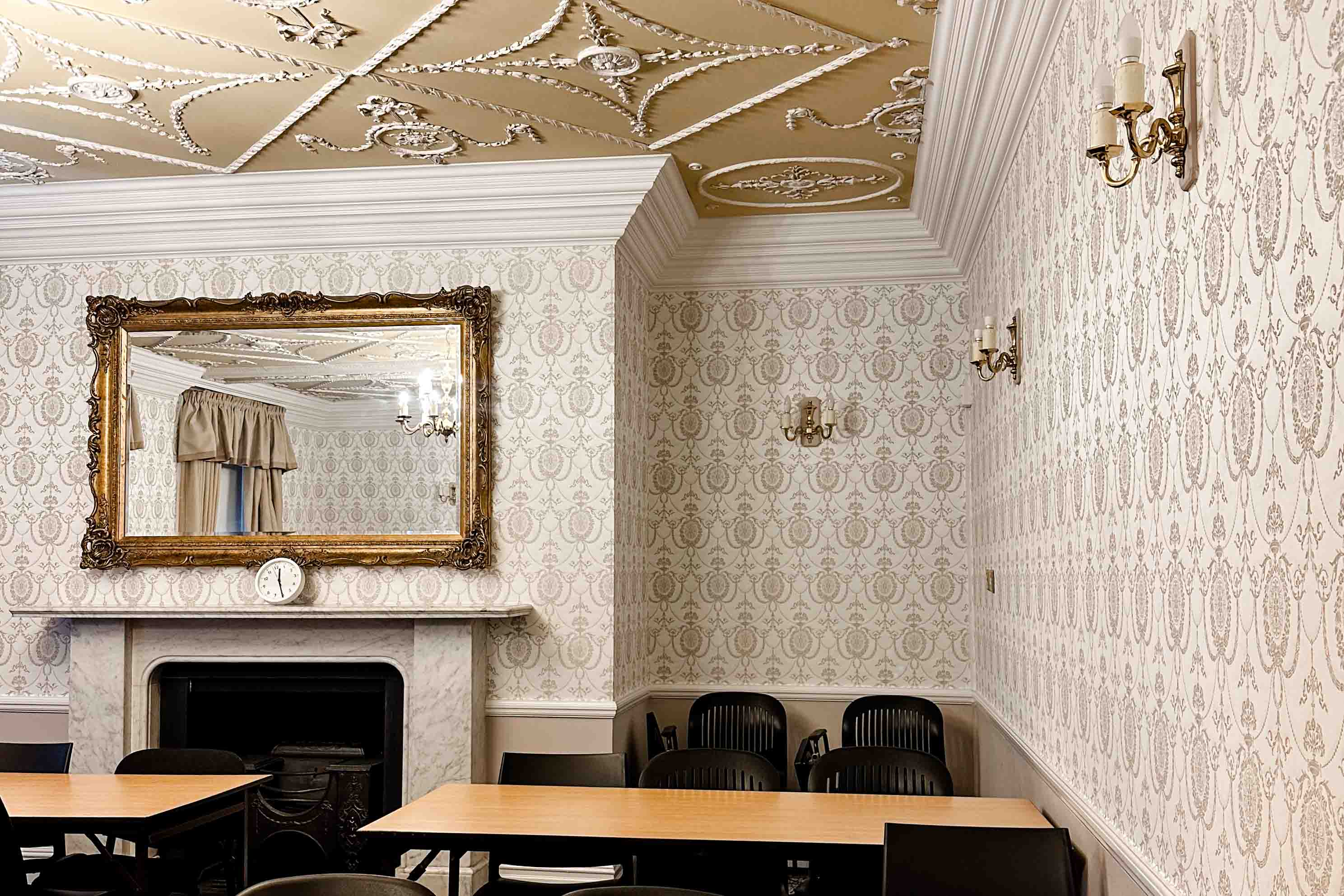 A view a historic classroom at FSU London with wallpaper and a fireplace.