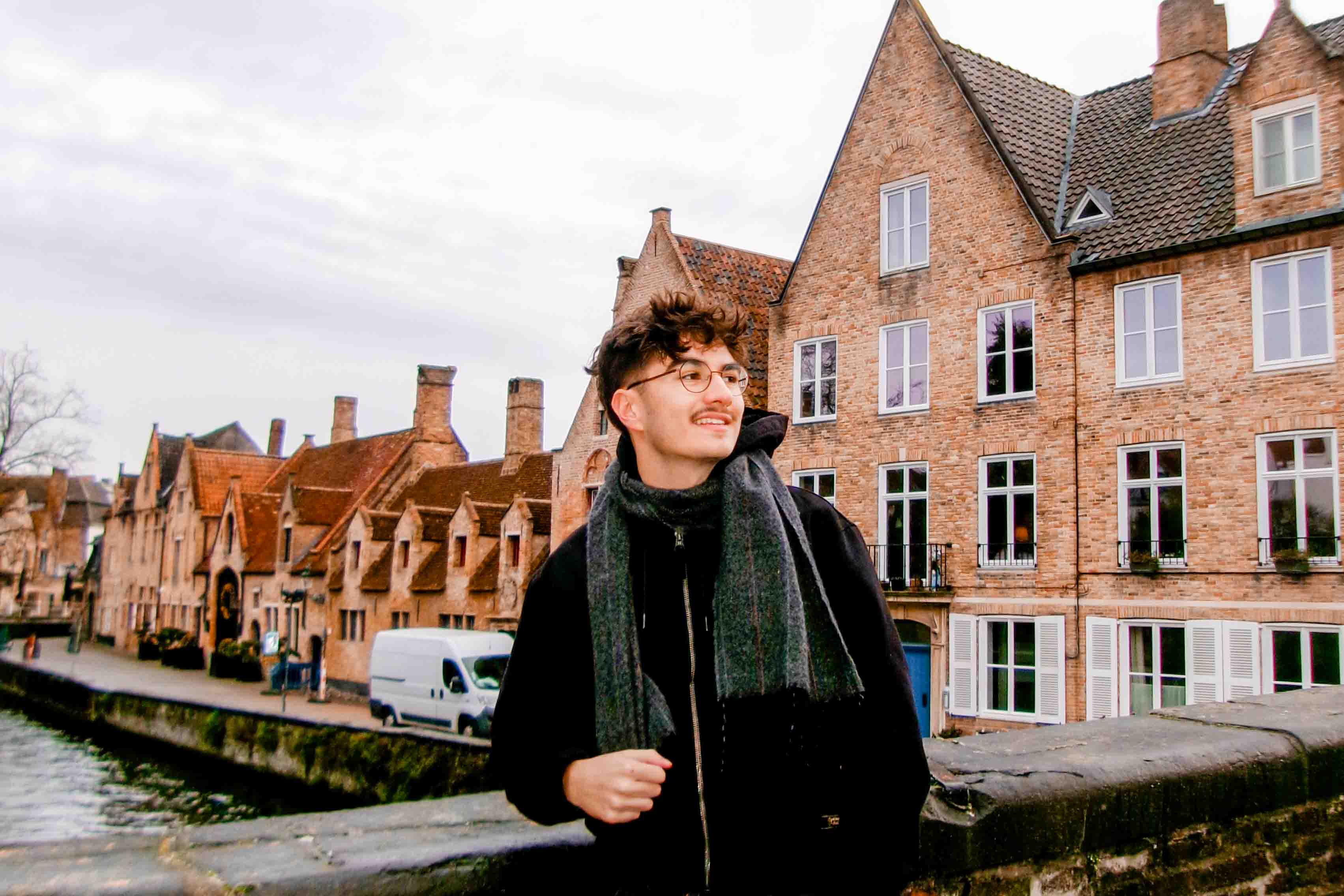 A student looks away from the camera with scenic UK streets in the background.