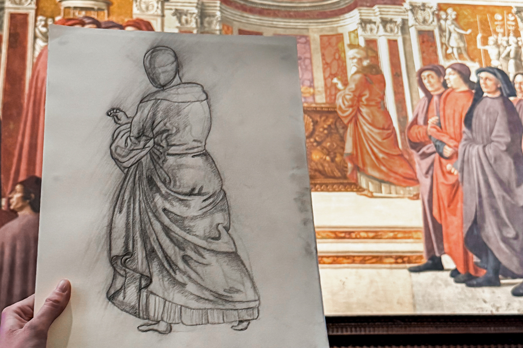 a student holding up a sketch of a museum art piece