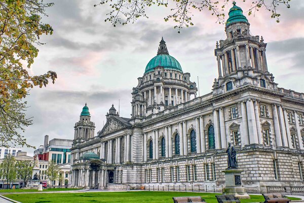A view of a historic building in Belfast and greenery around it.
