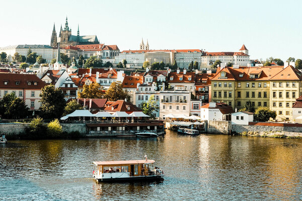 A view of historic buildings in Prague with water and a boat in the foreground.