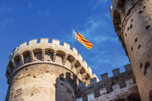A view of a Valencian flag flying over the Serrano Towers in Valencia.