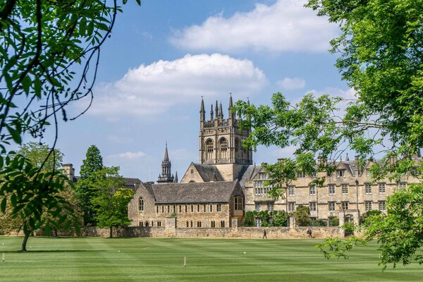 A view of Oxford with lawn and foliage in the foreground.