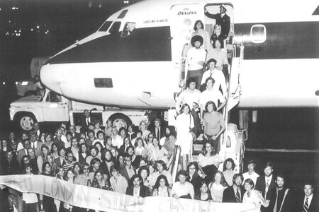 Dozens of students exiting an airplane in a black and white photo.
