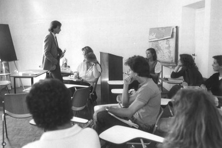 A black and white photos of a group of students sit in class in Florence while their professor lectures.